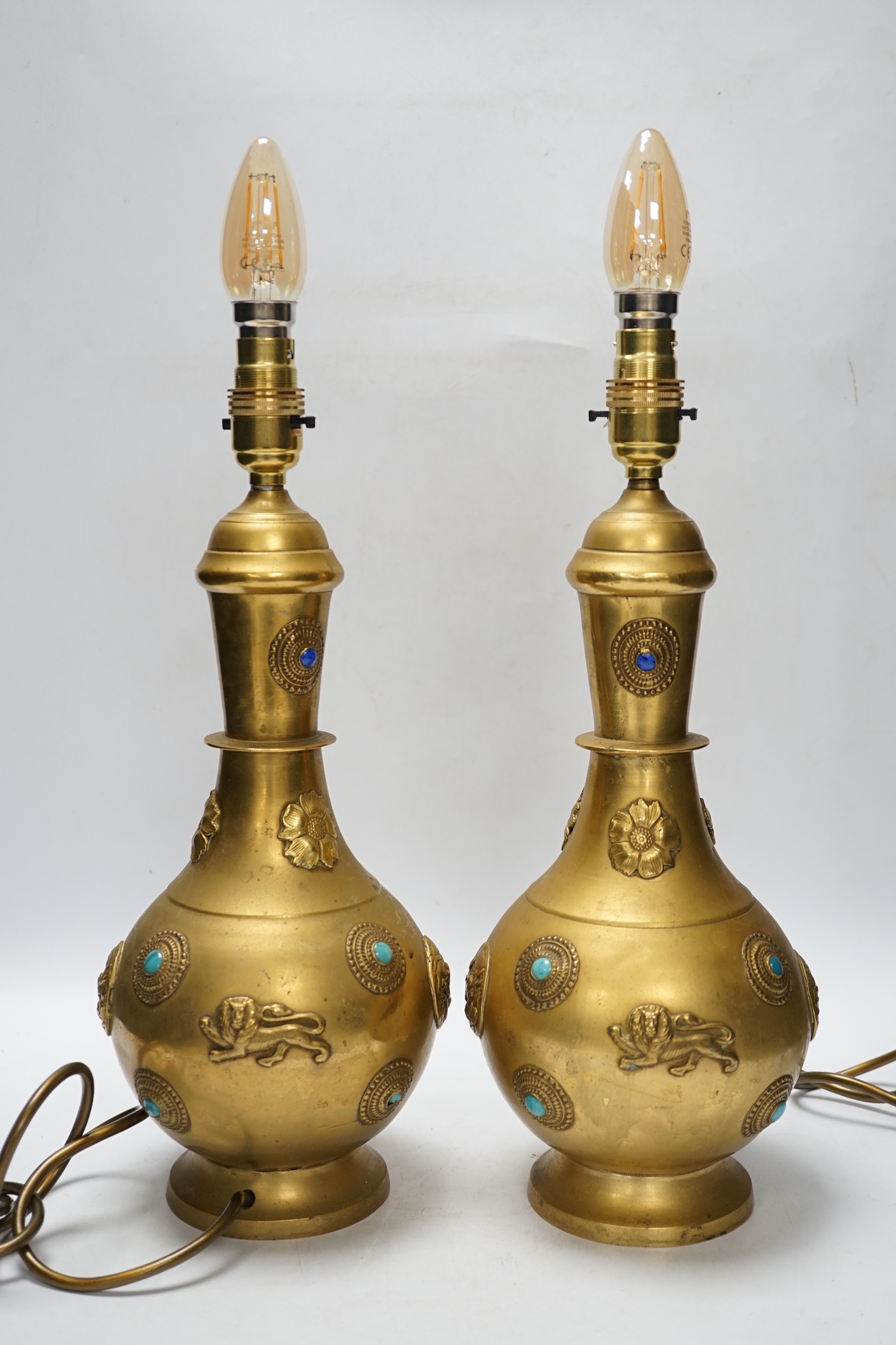 A pair of Sino-Tibetan gilt metal lamp bases set with cabochon stones